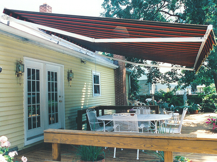 red striped awning that extends over patio of a yellow house